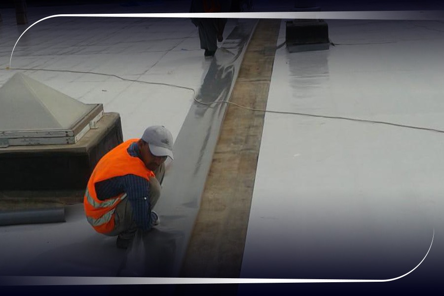 فني من شركة عوازل حائل يقوم بتنفيذ عزل مائي للأسطح باستخدام مواد بيتومين عالية الجودة